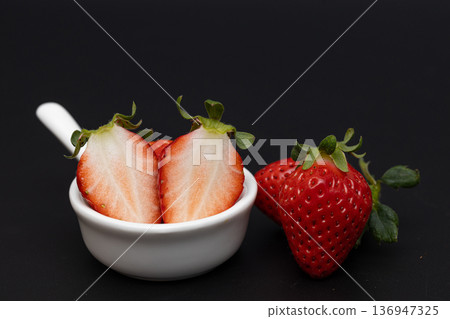 White cross section of a bright red strawberry. Stock photo of strawberries against a black background. 136947325
