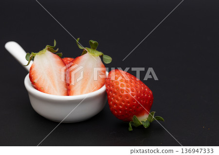 White cross section of a bright red strawberry. Stock photo of strawberries against a black background. 136947333