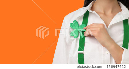 Woman wears white shirt and holds a shamrock for celebration Woman wears white shirt and holds a shamrock for celebration 136947612