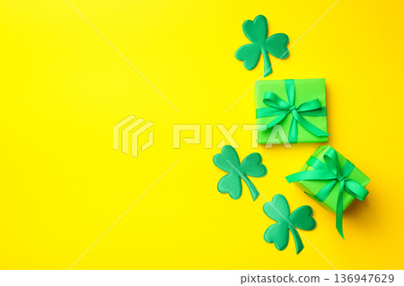 Three green wrapped presents with ribbons beside shamrock cutouts 136947629