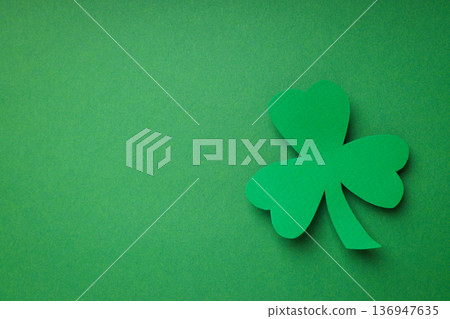 Green shamrock cutout against a solid green background 136947635