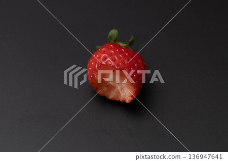 A bright red strawberry being eaten A bright red strawberry being eaten 136947641