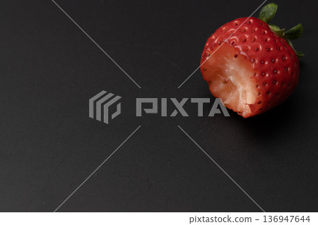 A bright red strawberry being eaten A bright red strawberry being eaten 136947644