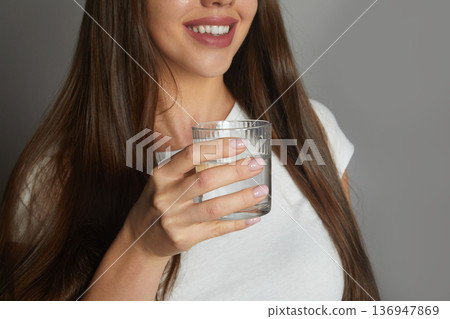 Close up smiling young woman holding glass of clean mineral water, happy beautiful female recommending drinking water Close up smiling young woman holding glass of clean mineral water, happy beautiful female recommending drinking water 136947869