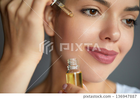 Skin Care. Woman Applying Essential Oil With Dropper On Face. Natural Cosmetic Product For Hydrated, Glowing And Healthy Facial Derma. Portrait Of Beauty Model With Perfect Skin 136947887