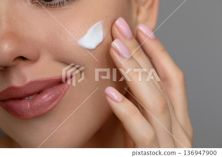 Woman with beautiful face touching healthy facial skin portrait. Beauty close up girl is applying a skincare cream. Hydration Woman with beautiful face touching healthy facial skin portrait. Beauty close up girl is applying a skincare cream. Hydration 136947900