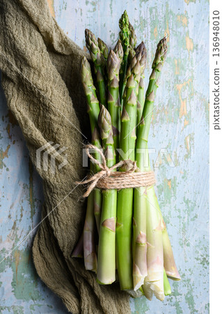 Bundle of green asparagus spears tides with kitchen cloth 136948010
