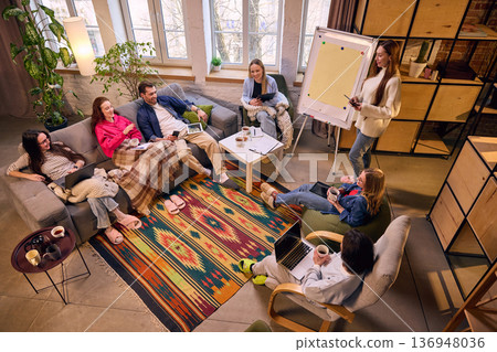 Informal startup meeting with laptops and coffee in loft interior. Informal startup meeting with laptops and coffee in loft interior. 136948036