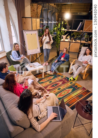 Team brainstorming session in cozy loft office with flip chart. 136948040