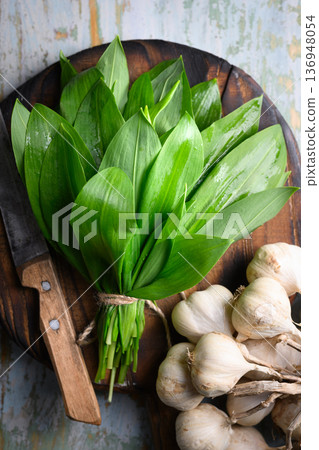 Fresh wild garlic leaves arranged on cutting board Fresh wild garlic leaves arranged on cutting board 136948054
