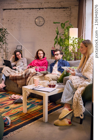 Team discussion in cozy loft office with coffee and notebooks. 136948076