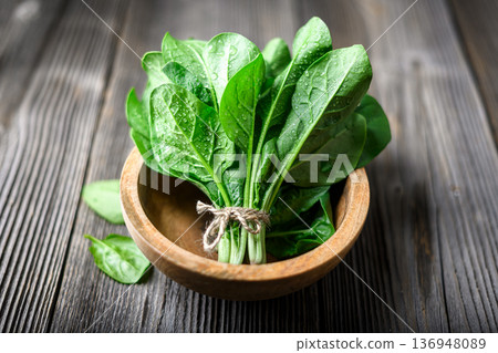 Organic spinach leaves in wooden bowl on textured wooden table Organic spinach leaves in wooden bowl on textured wooden table 136948089