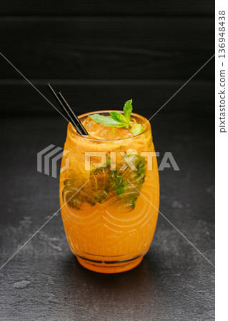 Orange refreshing cocktail with mint and ice in glass on dark background 136948438