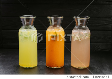 Three fresh homemade lemonades with ice and mint in glass bottles on dark background 136948441