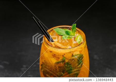 Orange refreshing cocktail with mint and ice in glass on dark background 136948443