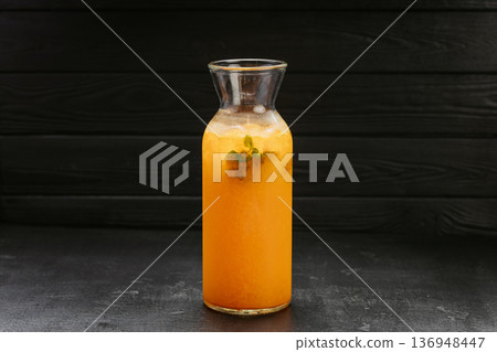 Fresh orange lemonade with mint and ice in glass bottle on dark background 136948447