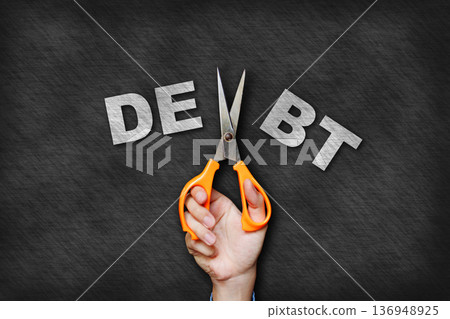 Concept of cutting unnecessary expenses with hand using scissors to cut away the word "debt." 136948925