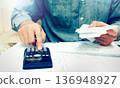 Young asian man using calculator and calculating bills to budgeting and tax calculation monthly expenses. budget management and accounting on table at home. 136948927