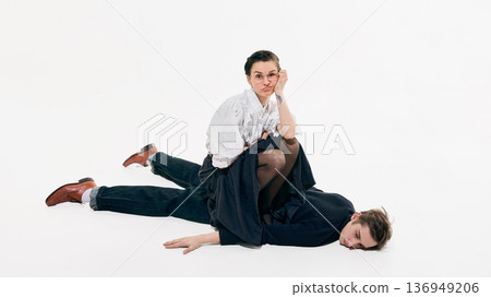 Confident business woman posing while sitting on man in minimal white space. 136949206