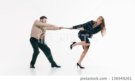 Businessman and businesswoman pulling object in opposite directions in dynamic studio pose on white background Businessman and businesswoman pulling object in opposite directions in dynamic studio pose on white background 136949261