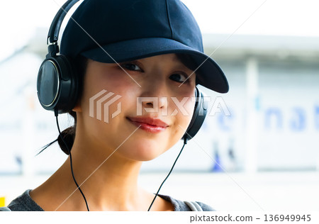 A woman enjoying music with headphones. Photo courtesy of Kansai International Airport (KIX). 136949945