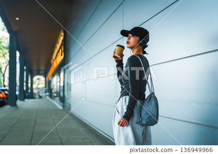 Woman drinking coffee and listening to music Woman drinking coffee and listening to music 136949966