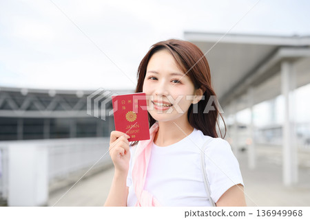 A woman holding a passport at the airport. Photo courtesy of Kansai International Airport (KIX). 136949968
