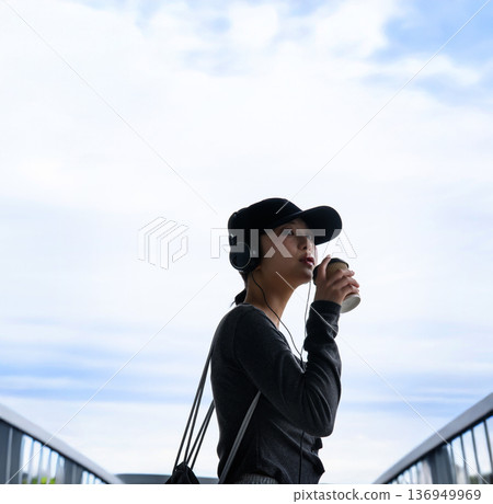 Woman drinking coffee outdoors Woman drinking coffee outdoors 136949969