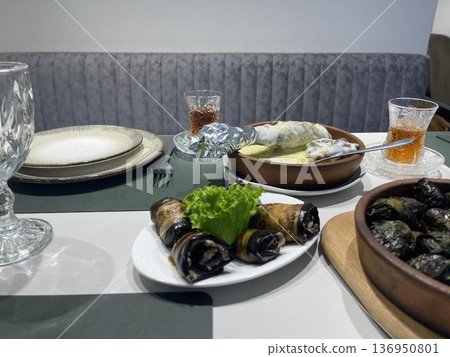 a table with plates of badrijani and glasses 136950801