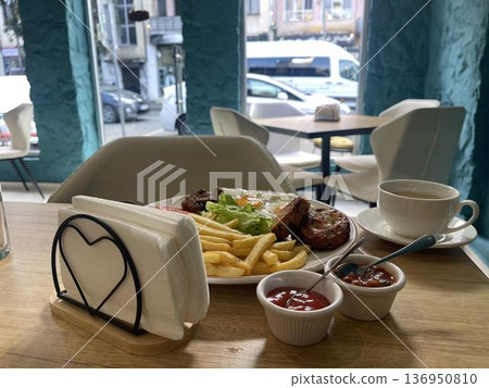 English breakfast with fried eggs, French fries, beans and meatloaf at a restaurant 136950810