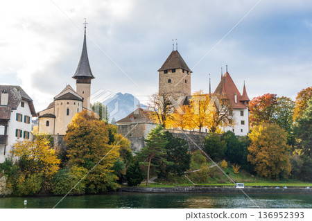 Historical architecture of Spiez Castle and church surrounded by yellow autumn trees on the lakeside. Spiez, canton of Bern, Switzerland 136952393