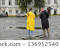 Two people in raincoats in a town square 136952540