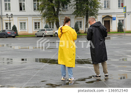 Two people in raincoats in a town square Two people in raincoats in a town square 136952540