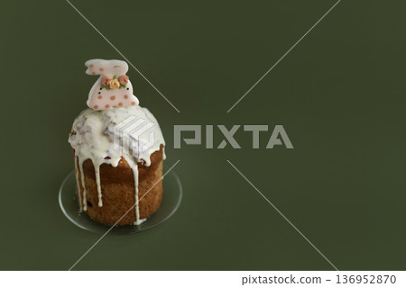 Spring Easter dessert decorated with rabbit figure and white icing against dark green backdrop, minimal festive concept Spring Easter dessert decorated with rabbit figure and white icing against dark green backdrop, minimal festive concept 136952870