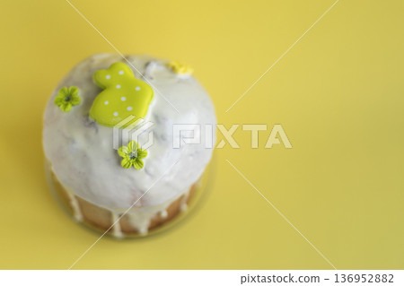 Festive Easter bread topped with icing and pastel green rabbit figure on yellow backdrop, joyful spring celebration concept 136952882