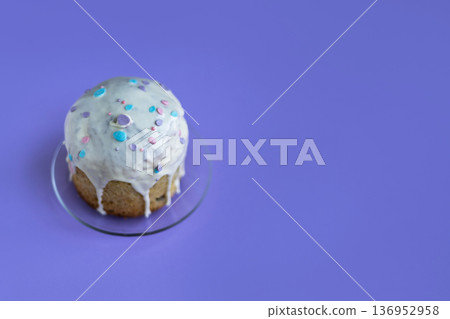 Easter cake topped with glossy icing and decorative sugar drops on vibrant purple background, festive spring dessert concept Easter cake topped with glossy icing and decorative sugar drops on vibrant purple background, festive spring dessert concept 136952958