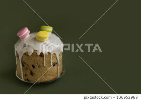 Holiday Easter dessert decorated with icing drops and colorful macarons against deep green backdrop, sophisticated spring concept 136952969