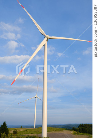 Wind Turbines on Hilltop Against Blue Sky 136955397