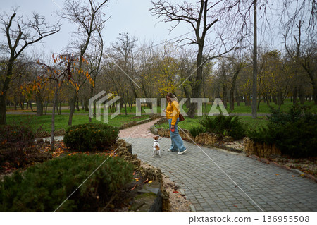 Woman talking on phone with dog in autumn park Woman talking on phone with dog in autumn park 136955508