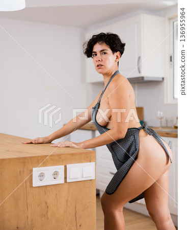Naked woman in apron posing in kitchen Naked woman in apron posing in kitchen 136955964