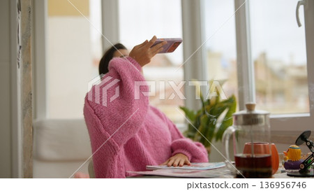 Young woman content creator taking coffee selfie in pink sweater 136956746