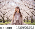 A high school girl wearing a stylish uniform walking along a row of cherry blossom trees 136956858