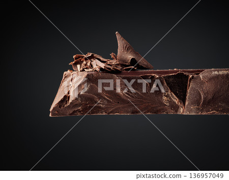 Large piece of dark chocolate and falling chocolate crumbs. Large piece of dark chocolate and falling chocolate crumbs. 136957049