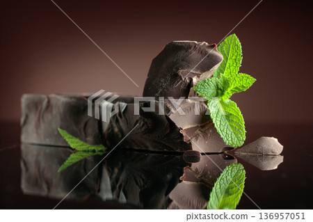Large piece of dark bitter chocolate with mint on a black reflective background. 136957051