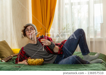 Young Caucasian teenage woman enjoying a peaceful moment at home. She watches TV on bed. Leisure lifestyle. Mid shot Young Caucasian teenage woman enjoying a peaceful moment at home. She watches TV on bed. Leisure lifestyle. Mid shot 136957510