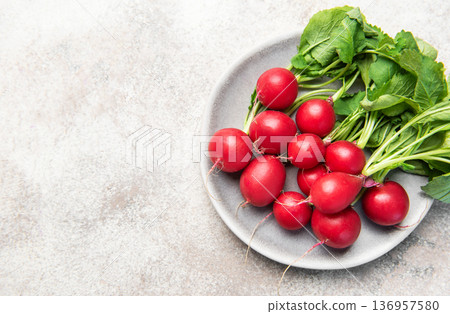 Fresh spring radishes with green leaves on plate Fresh spring radishes with green leaves on plate 136957580