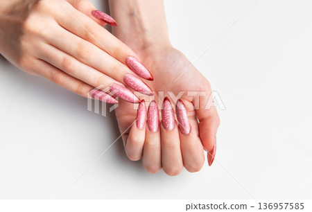 Woman's hands showing long pink glitter stiletto nails 136957585