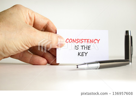 Consistency is the key symbol. Concept words Consistency is the key on beautiful white card. Beautiful white background. Businessman's hand. Business consistency is the key concept. Copy space. 136957608