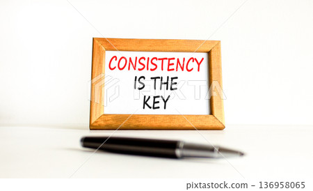 Consistency is the key symbol. Concept words Consistency is the key on beautiful wooden picture frame. Beautiful white background. Black pen. Business consistency is the key concept. Copy space. 136958065