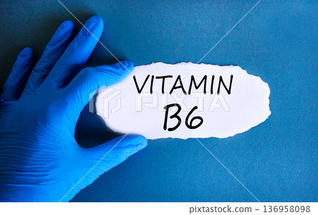 Vitamin B6 symbol. Concept words Vitamin B6 on beautiful white paper. Doctor's hand in blue medical glove. Beautiful blue background. Medical healthy lifestyle Vitamin B6 concept. Vitamin B6 symbol. Concept words Vitamin B6 on beautiful white paper. Doctor's hand in blue medical glove. Beautiful blue background. Medical healthy lifestyle Vitamin B6 concept. 136958098